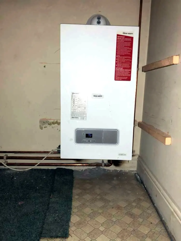 A new Glow-worm combi boiler on a wall, its pipework running along below